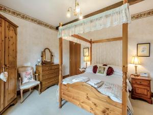 a bedroom with a wooden canopy bed and a dresser at Rose Cottage - Lpd in Ireby