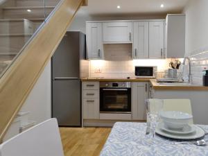 a kitchen with white cabinets and a table with a table cloth at Cornel Clyd Cosy Corner in Cilcennin