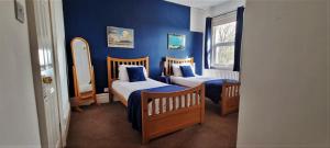 a blue room with two beds and a mirror at The Weir Hotel in Walton-on-Thames
