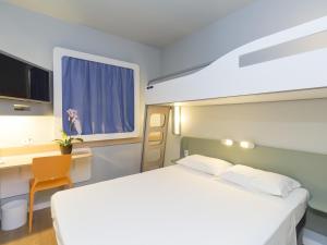 a bedroom with a white bed and a desk and a window at ibis budget Blumenau in Blumenau