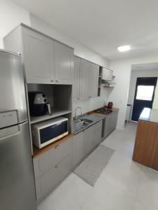 a kitchen with white cabinets and a stainless steel refrigerator at Apartamento Novo 5min da Oktoberfest in Blumenau