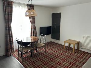 a dining room with a table and chairs on a rug at Chloes Holiday Apartments in Inverness