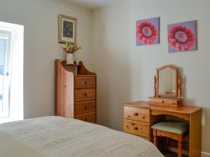a bedroom with a bed and a dresser and a mirror at Holly - Apartment in Aberfoyle +10 photos