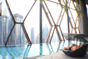 a person laying in a hammock next to a swimming pool at Hospitality Service Suites Scarlitz KLCC in Kuala Lumpur