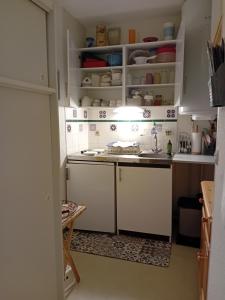 Una pequeña cocina con gabinetes blancos y un fregadero. en Sur le GR10 et autres sentiers à Aulus-les-Bains, en Aulus-les-Bains