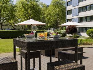 a table with two chairs and an umbrella at Mercure Hotel Mannheim am Friedensplatz in Mannheim