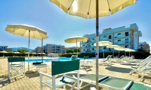 a group of chairs and umbrellas next to a pool at ISA - Apartments for 6 people, 2 bedrooms, in Residence Mirto And Corbezzolo with swimming pool in San Vincenzo in San Vincenzo