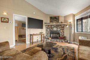 a living room with a fireplace and a flat screen tv at Hideaway Chalet - Hot Tub in the Treetops, Arcade Games, + Close to Ober Mountain! in Chalet Village