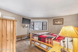 a bedroom with a bed and a table with a lamp at Hideaway Chalet - Hot Tub in the Treetops, Arcade Games, + Close to Ober Mountain! in Chalet Village +34 photos