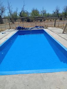 a blue swimming pool with a fence in the background at Cabañas bola 8 in Barreal