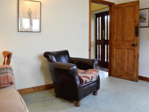 a black leather chair sitting in a living room at The Old School Penallt in Mitchel Troy