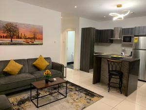un salon avec un canapé et une cuisine dans l'établissement Embassy Gardens Luxury Suites, à Accra