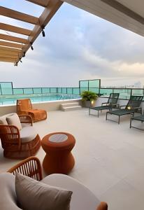 a patio with chairs and tables on a roof at Apê 100 metros do mar - Praia in Maceió