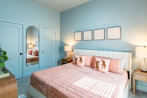 a bedroom with blue walls and a bed with pink pillows at The Golden Tiger in Baton Rouge