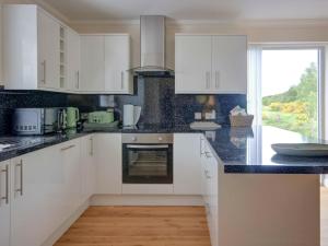 a kitchen with white cabinets and black counter tops at Darna House in Tain +14 photos