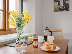 a table with eggs bread and a vase of flowers at Daisy Cottage - Uk31294 in Locking +15 photos