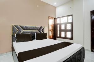a bedroom with a large white bed with a window at Hotel O The Happy Homestay in Morādābād