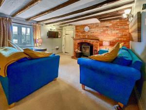 - un salon avec deux canapés bleus et une cheminée dans l'établissement Meadow Cottage, à Helhoughton