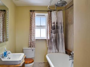 a bathroom with a tub and a toilet and a sink at Bradcar Farm Cottage in Snetterton +3 photos