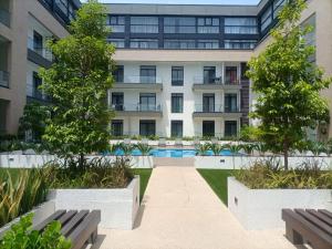 un immeuble d'appartements avec des arbres et des bancs devant lui dans l'établissement Embassy Gardens Luxury Suites, à Accra