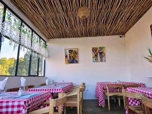 a restaurant with red and white checked tables and windows at La Casa Di Mantasoa - Lodge by the Lake in Mantasoa
