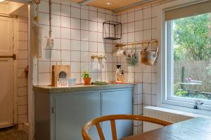 ヴェストカペレにあるHello Zeeland - Tiny House FlipFlopのピンクのタイル張りの壁とテーブルと窓のあるキッチン