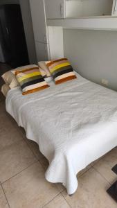 a white bed with two pillows on top of it at Rodalquilar in Mar del Plata