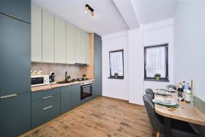 a kitchen with blue cabinets and a table with chairs at Primaverii Dream Residence in Chişoda