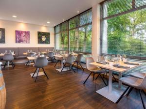 a restaurant with tables and chairs and large windows at Sunday Hotel Bielefeld Johannisberg in Bielefeld