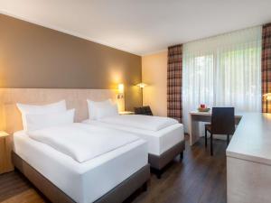 a hotel room with two beds and a desk at Sunday Hotel Bielefeld Johannisberg in Bielefeld