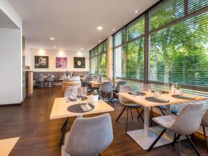 a restaurant with tables and chairs and large windows at Mercure Hotel Bielefeld Johannisberg in Bielefeld