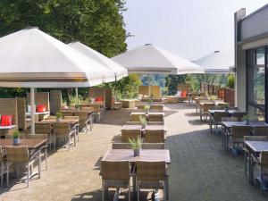 a row of tables and chairs with umbrellas at Sunday Hotel Bielefeld Johannisberg in Bielefeld