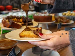 a person holding a plate with a piece of cake at ibis Styles Taubate in Taubaté