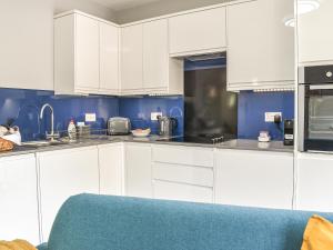 cocina blanca con paredes azules y armarios blancos en The Den, en Herne Bay