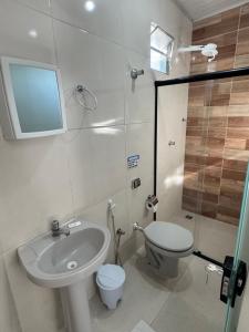 a bathroom with a sink and a toilet and a shower at Pousada La Ville in Itapetinga