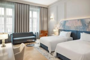 a hotel room with two beds and a chair at H15 Palace, a Luxury Collection Hotel, Krakow in Krakow