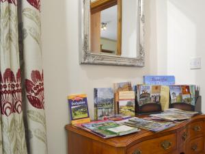 ein Tisch mit Büchern und einem Spiegel an der Wand in der Unterkunft Railway Cottage in Brassington