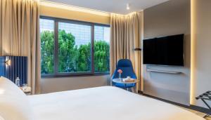 a hotel room with a large bed and a television at Pullman Madrid Airport & Feria in Madrid