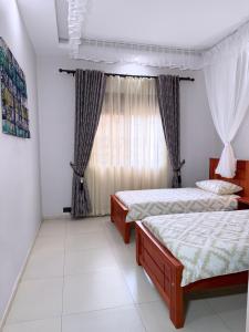 a bedroom with two beds and a window at Jay Jay Homes in Kampala