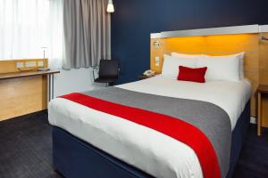 a hotel room with a large bed with a red pillow at Holiday Inn Express Hemel Hempstead by IHG in Hemel Hempstead