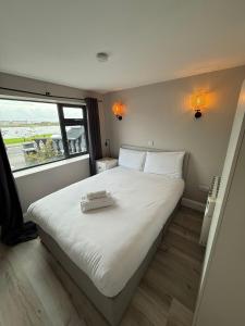 a bedroom with a large white bed with a large window at Urban Lakeside Galway City Centre in Galway