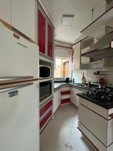 a kitchen with white appliances and red cabinets at Casa Laranja Imbituba in Imbituba +22 photos