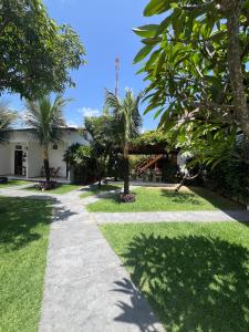 a walkway in front of a house with palm trees at Bosque Cumbuco Pousada in Cumbuco