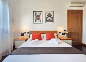 a bedroom with a large white bed with red pillows at Sunset Escape Apartment - panoramic terrace in Fiumicino