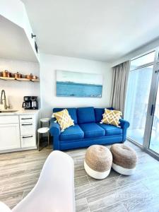 a living room with a blue couch and a kitchen at Waves of Grace Apartment Oceanfront SeaWatch Resort in Myrtle Beach