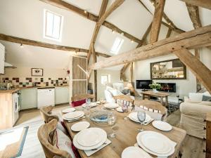 a kitchen and living room with a wooden table and chairs at The West Barn in Hanley Castle