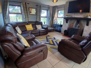 a living room with a leather couch and a fireplace at Oaktree Manor - BBQ, games rooms and pet friendly in Castlewellan