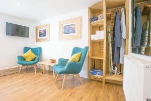 a room with two blue chairs and a table at Doolittle in Porthleven