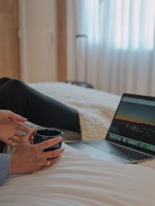 Una mujer sosteniendo una taza de café junto a una computadora portátil. en Montano Boutique Suites, en El Calafate