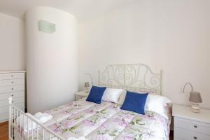 a white bedroom with a white bed with blue pillows at The Balcony of the Lake in Lecco